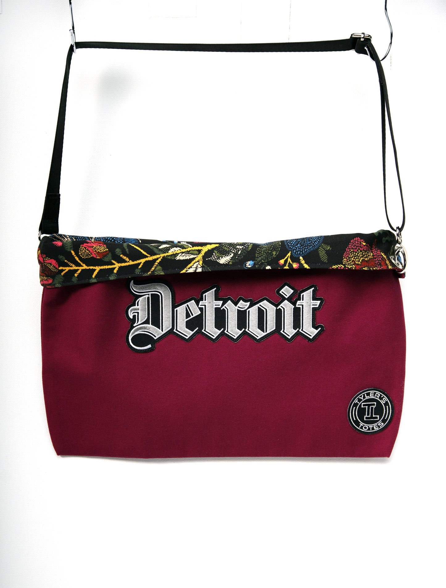 Raspberry colored square tote with "Detroit" patch in Old English font and black floral interior.