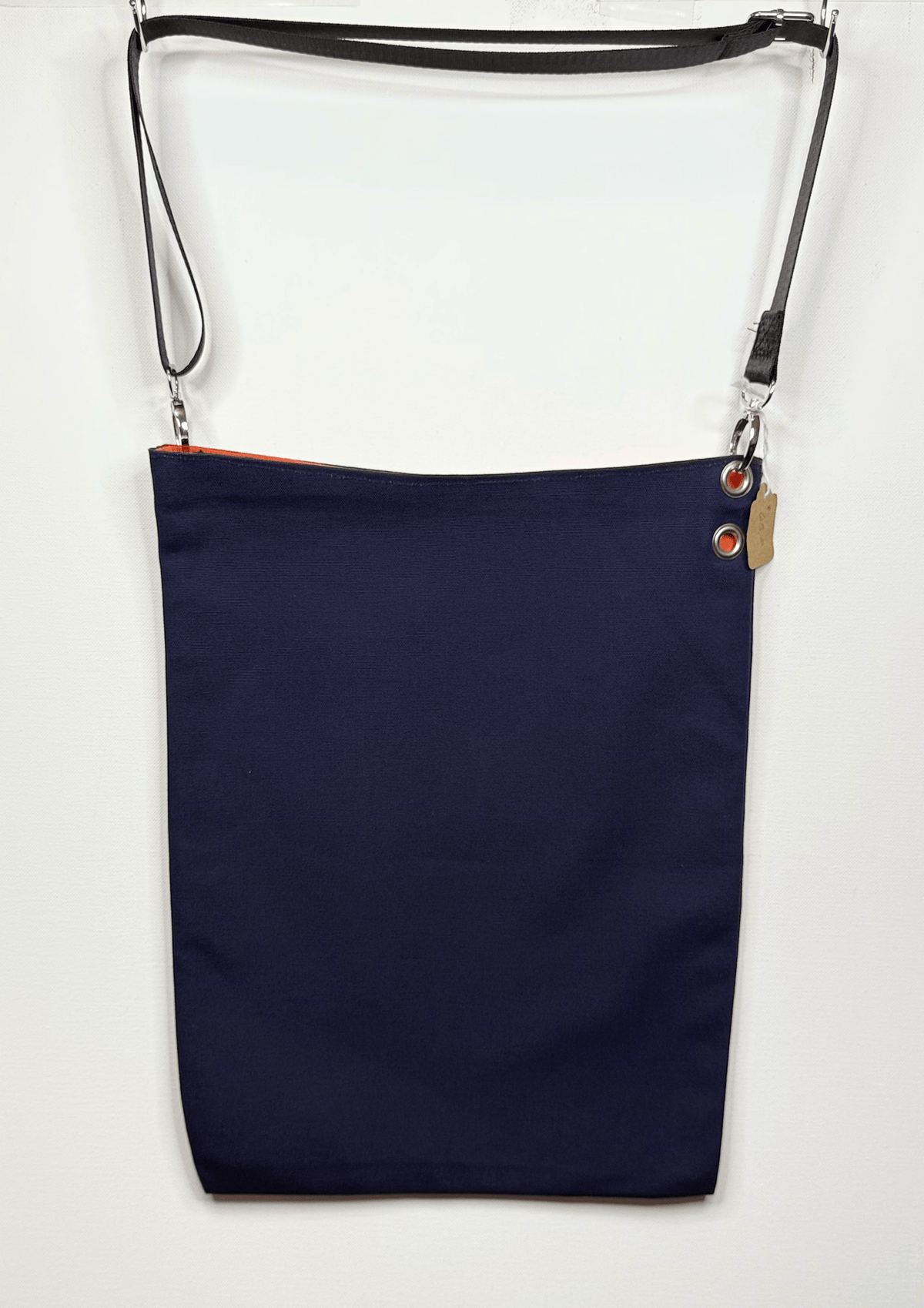 A navy blue canvas shoulder bag with a black adjustable shoulder strap and silver metal hardware, shown against a plain white background.