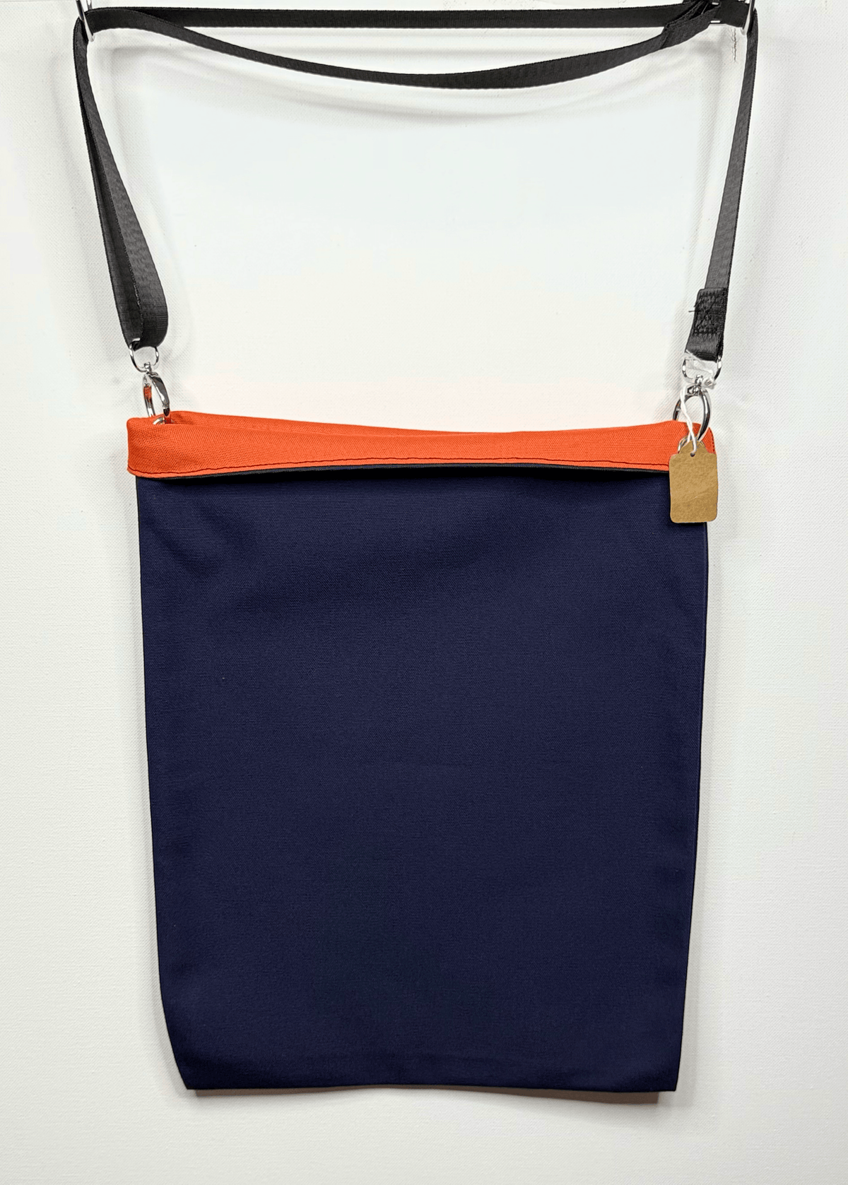 A navy blue canvas shoulder bag with a bright orange foldable brim and a black adjustable strap, shown against a plain white background.