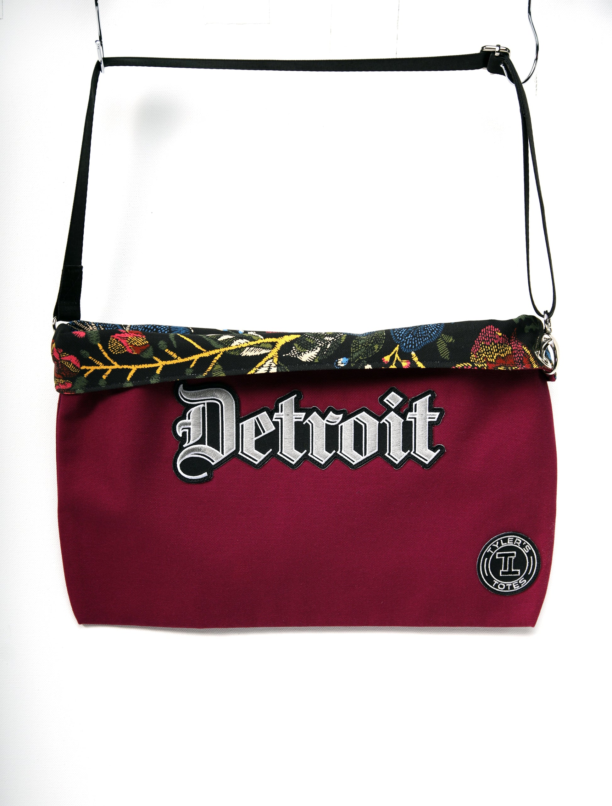Raspberry colored square tote with "Detroit" patch in Old English font and black floral interior.